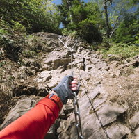 上州武尊山の行者返しで鎖を握る登山者の険しい岩場での登頂の写真