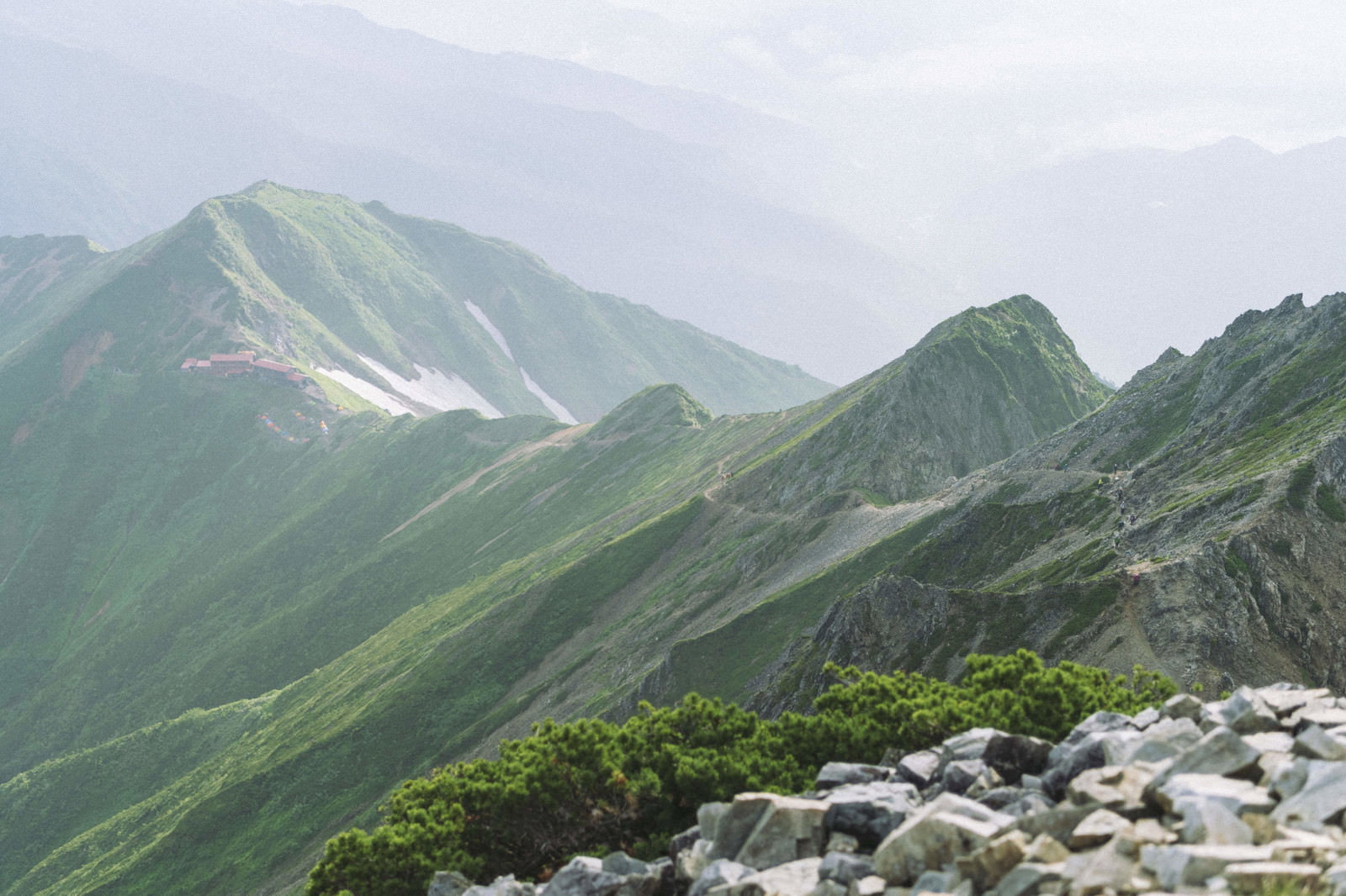 五竜岳の稜線から見た緑豊かな山々と曇り空の風景