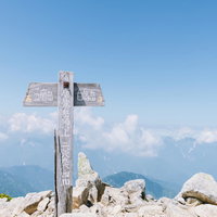 北アルプス唐松岳山頂の白い指導標と五竜岳の眺望の写真
