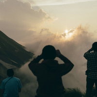 五竜岳の山頂で夕日を撮影する登山者たちのシルエットの写真