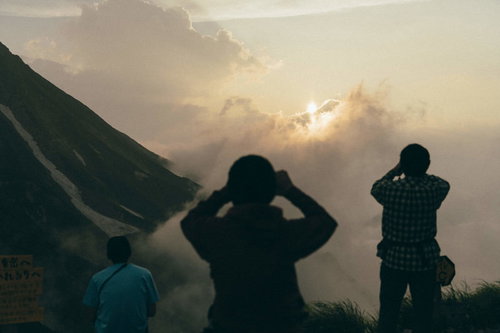 五竜岳の山頂で夕日を撮影する登山者たちのシルエット