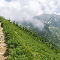 牛首下部から見る雲に包まれた五竜岳と登山道の写真