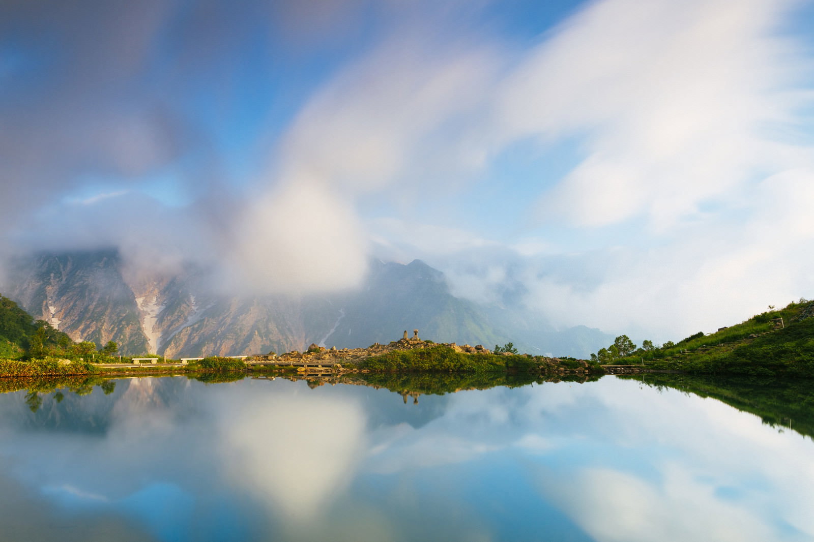 朝焼けの空と雲が水面に映る八方池の風景