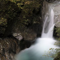 岩場を流れるシルキーな水の渓流と白い水飛沫の写真
