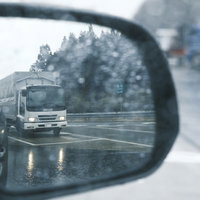 雨の日のバックミラーに映るトラックの後方確認の写真
