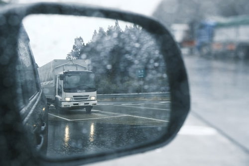 雨の日のバックミラーに映るトラックの後方確認