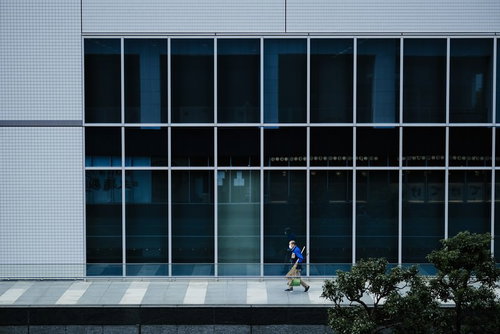 ビルの脇を歩く清掃員の男性、窓ガラス清掃