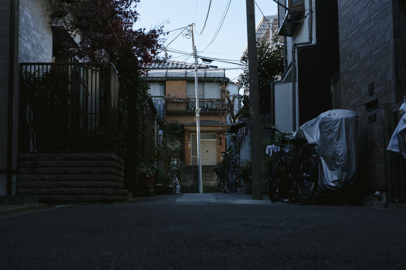 住宅地の路地に立つ傾いた電柱と自転車