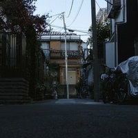 住宅地の路地に一本立つ傾いた電柱と自転車のある風景の写真