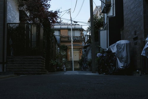 住宅地の路地に一本立つ傾いた電柱と自転車のある風景