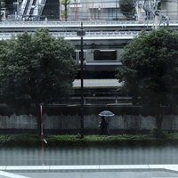 黒い傘をさして雨の歩道を歩く通行人の街並みを背景にした雨天時の風景の写真