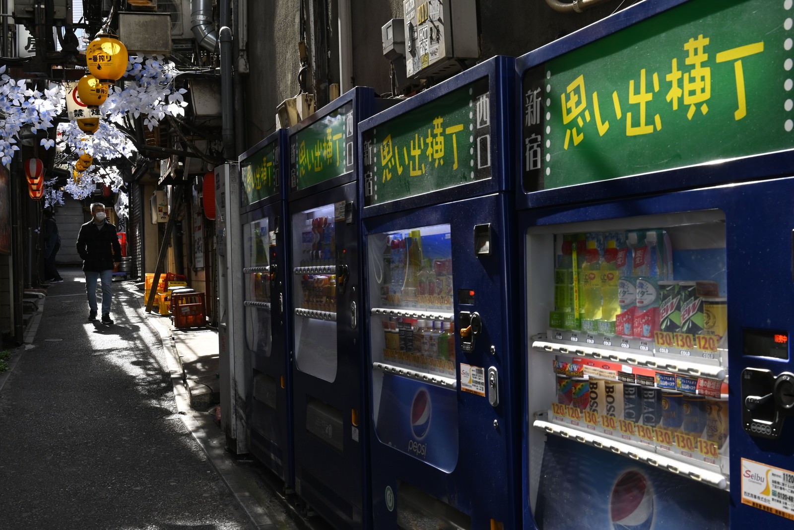 思い出横丁の狭い路地裏に自動販売機と飲食店の看板が並ぶ夜の風景