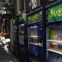 思い出横丁の路地裏に立ち並ぶ自動販売機と飲食店の看板の写真