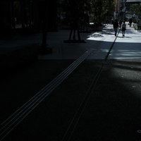 暗い街の歩道を歩く人々のシルエットの写真