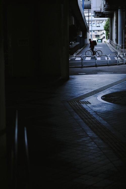 暗い街中を走るウーバーイーツの配達員、夜間配達業務の風景