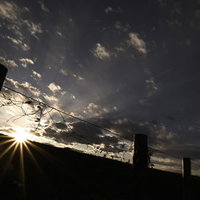 河川敷に降りる夕暮れの光芒と夕日のシルエット風景の写真