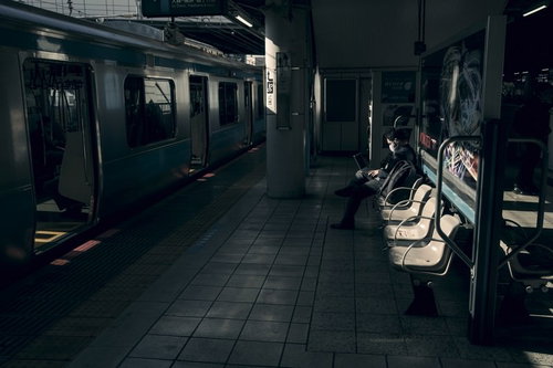 駅のホームで夕暮れ時に仕事をするビジネスマン