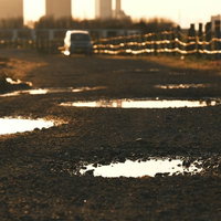 夕暮れの砂利道に広がる水たまりの写真