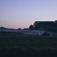 夕暮れの河川敷を散歩する人のシルエットの写真