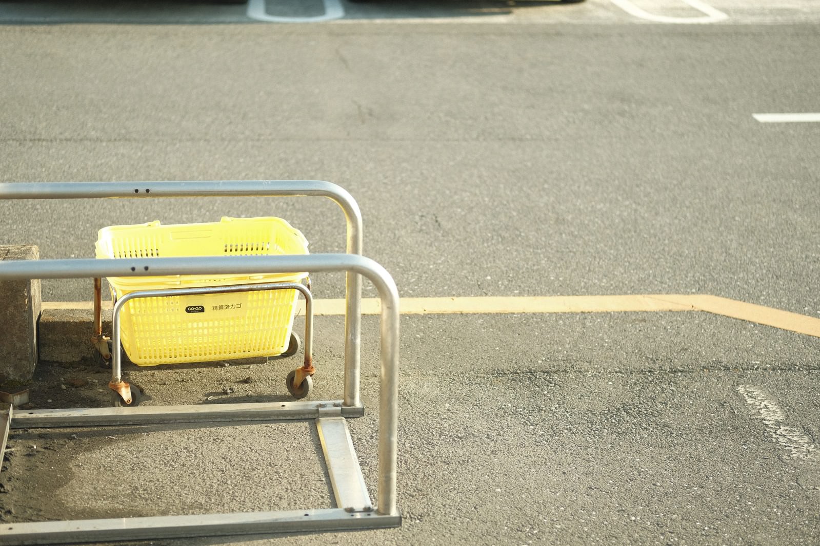 駐車場に設置された買い物カート置き場に黄色いショッピングカートが並んでいる