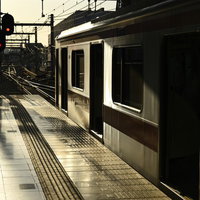 朝日に照らされる駅ホームに停車する白い電車の写真