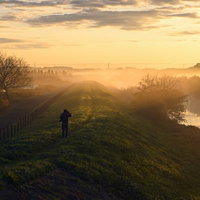 早朝の朝焼けを撮影するカメラマンのシルエットの写真