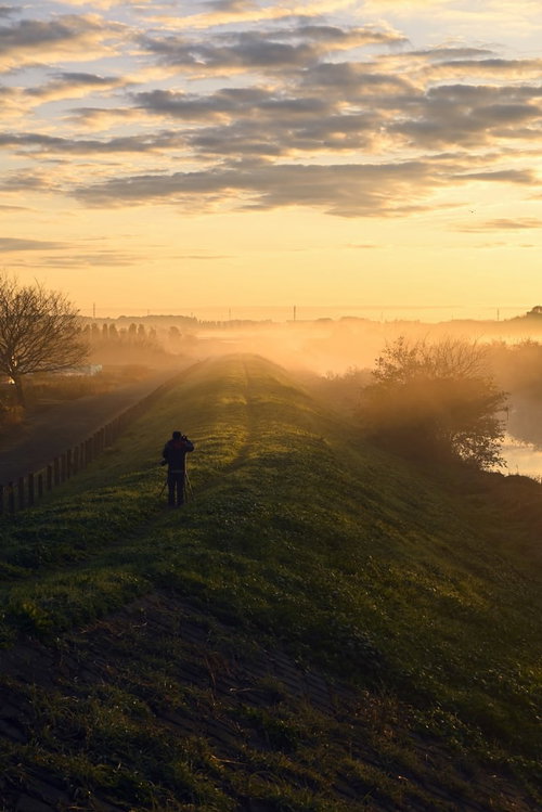 早朝の朝焼けを撮影するカメラマンのシルエット
