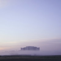 朝霧から顔を出す建物と朝焼けの土手・河川敷の風景の写真