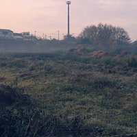 朝靄に包まれた丘陵地帯に立つ朝焼けの鉄塔の写真