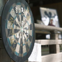 神社の境内に置かれた木製の円形ダーツボードの写真