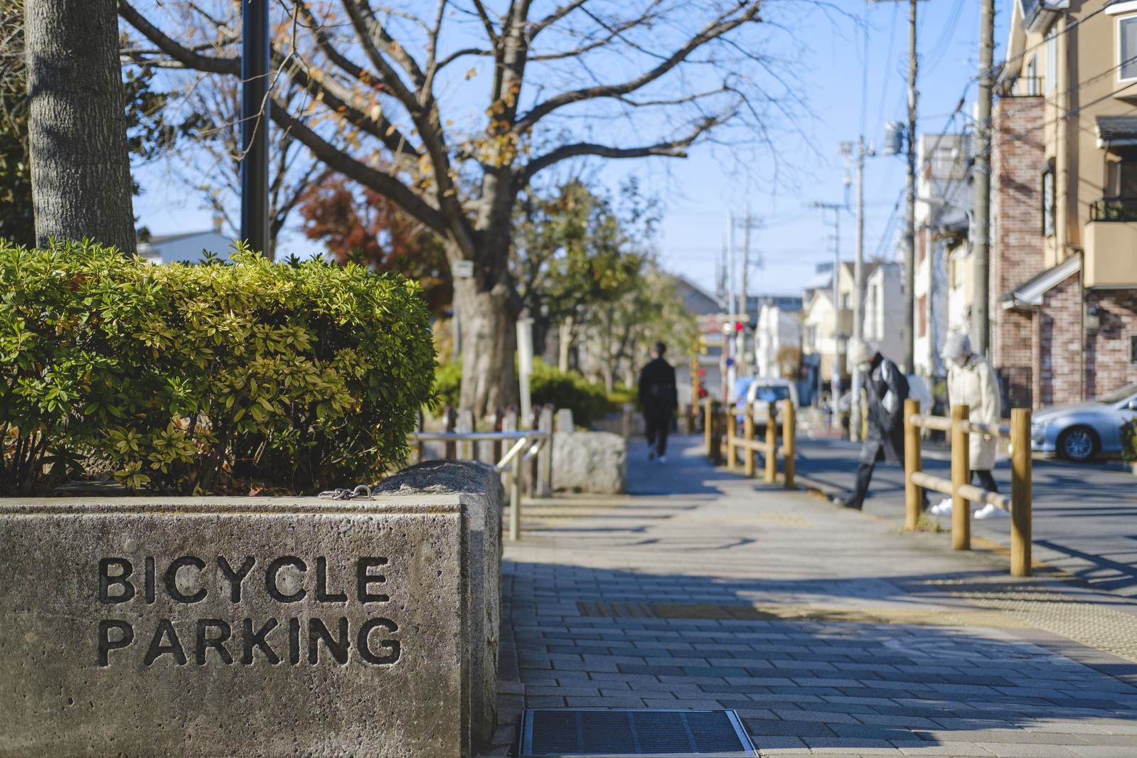 歩道に設置されたBICYCLE PARKINGの案内表示と街並み