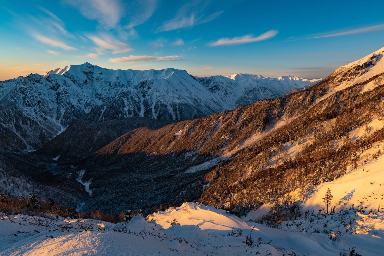 西穂高岳から見た冬の笠ヶ岳と朝焼けに染まる雪山の風景