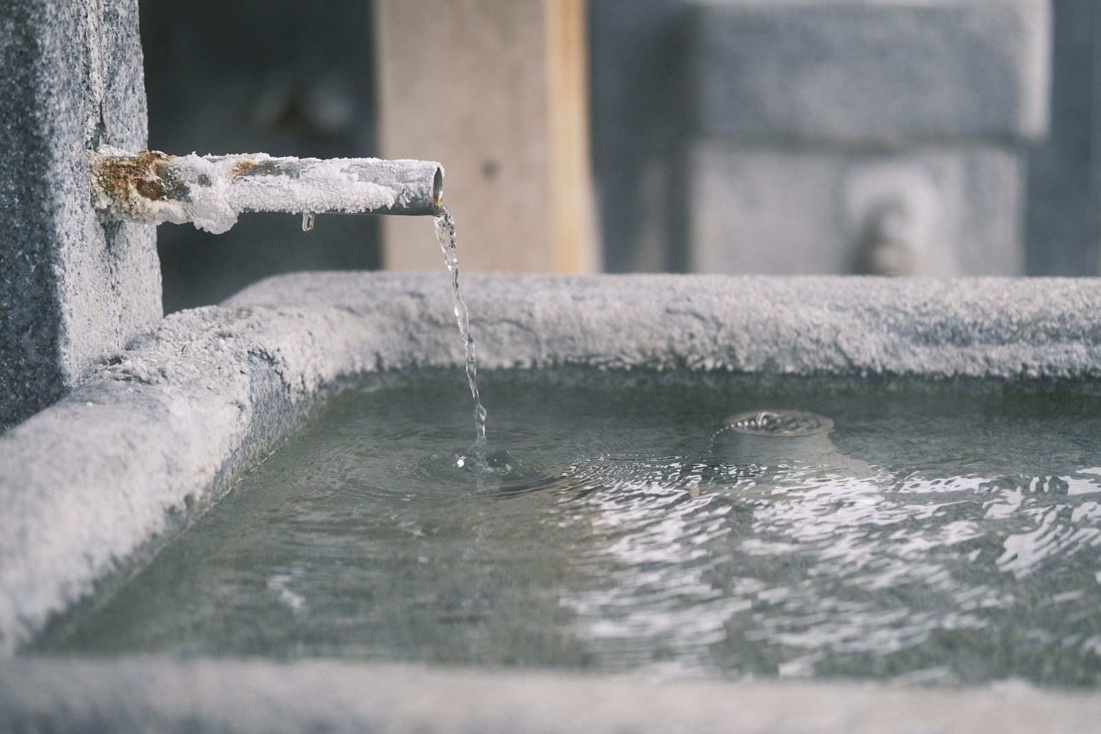 古い給水栓から流れ出る温泉水と白く結晶した石造りの施設