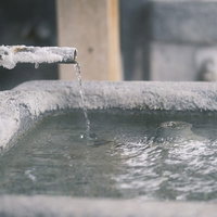 道端の飲泉スポット、白い結晶が付着した古い給水栓の写真