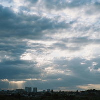 薄明光線が差し込む騒がしい空と東京の街並みの写真