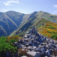 ケルンの向こうに見える日本百名山・大朝日岳の山頂の写真
