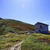 大朝日岳避難小屋と山頂方面の山稜線の景色の写真
