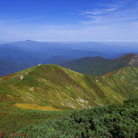 大朝日岳から小朝日岳へと続く緑の稜線と日本百名山の山々の写真
