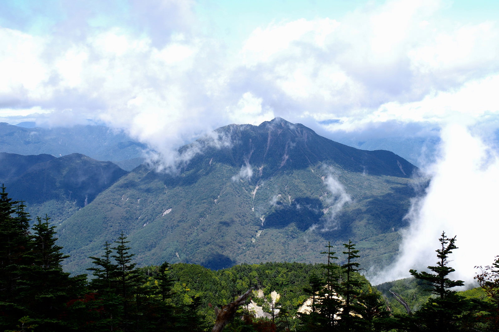 男体山山頂から見る太郎山の山岳風景、雲に包まれた山々と緑の樹木