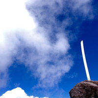 男体山山頂の岩に突き刺さる刀の刃と青空の景色の写真