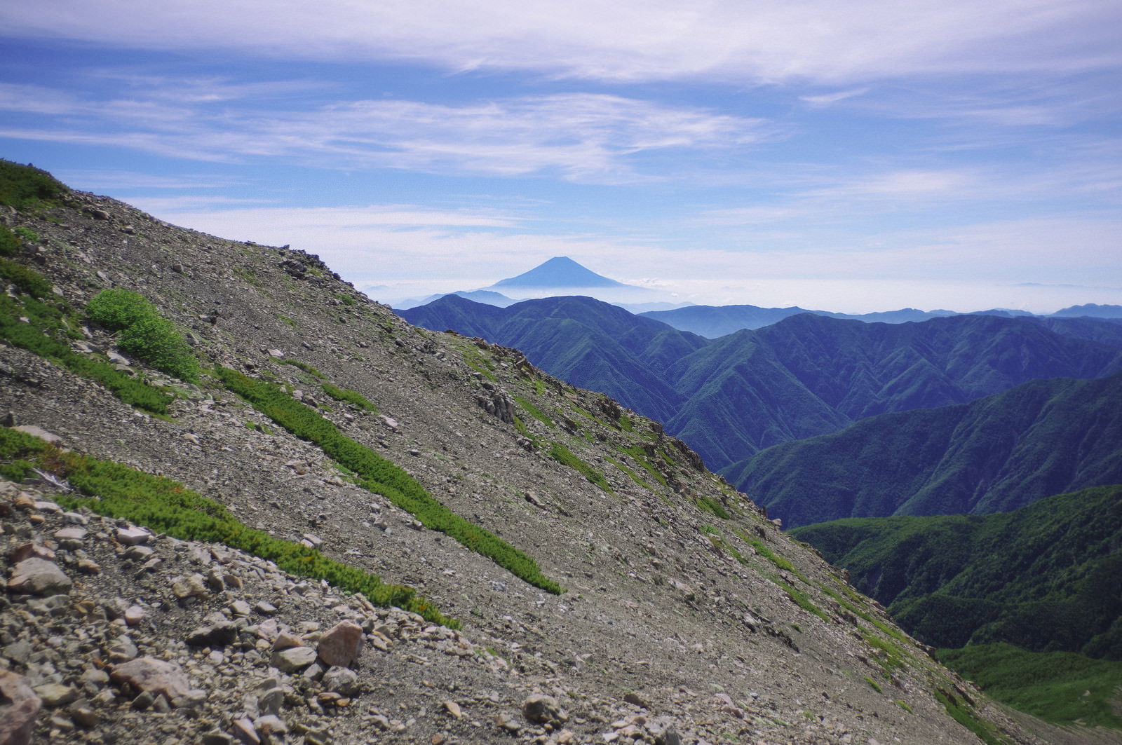 聖岳の登山道にある石の斜面と遠くに見える富士山の風景