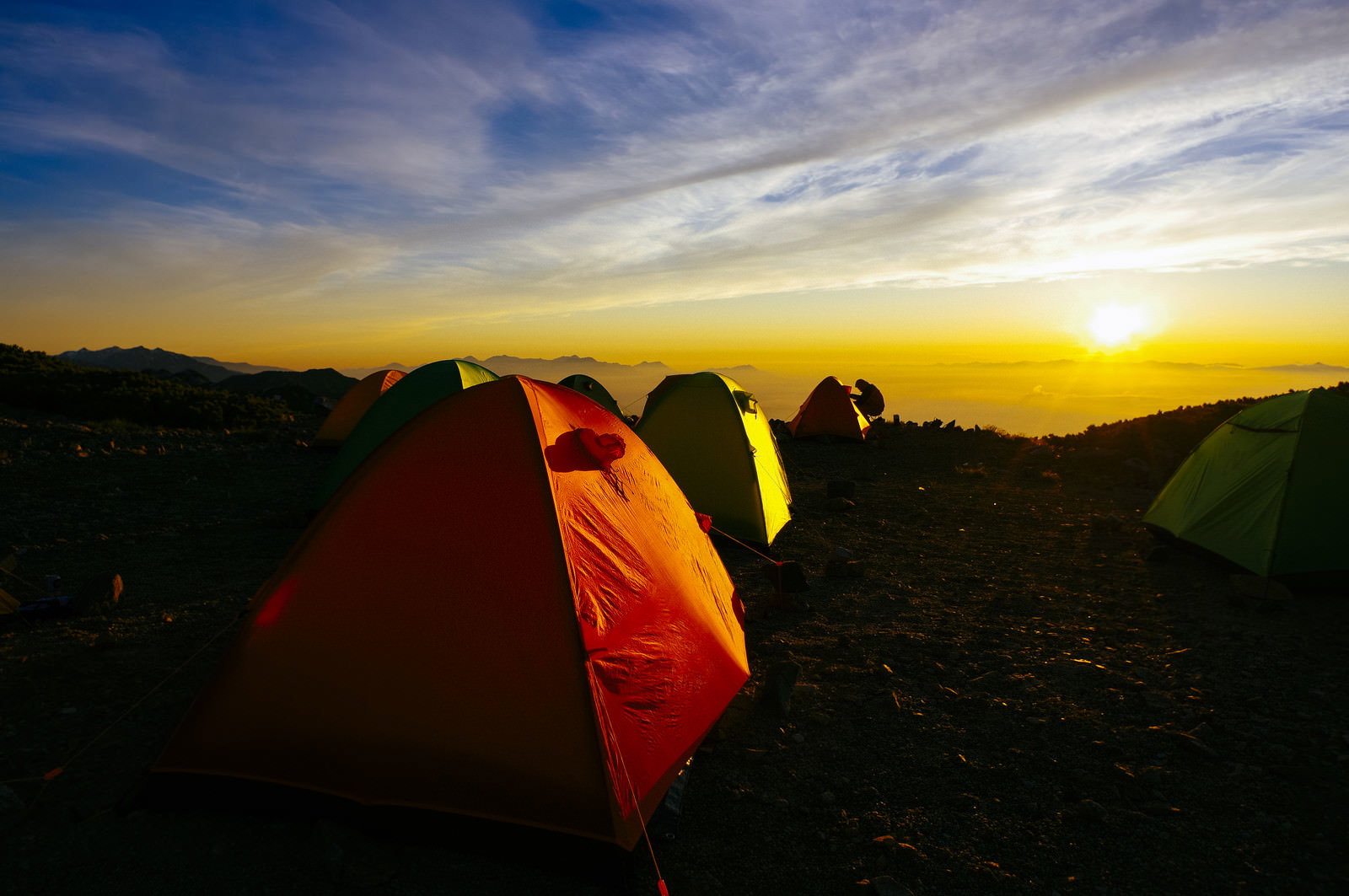 大天井岳のテント場に並ぶテントと朝焼けに染まる常念岳の山並み