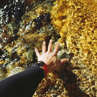 常念岳の山の沢で冷たい水に手を浸す登山者の写真