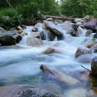 常念岳一の沢の白く流れる渓流と登山道、岩場と深緑の自然風景の写真