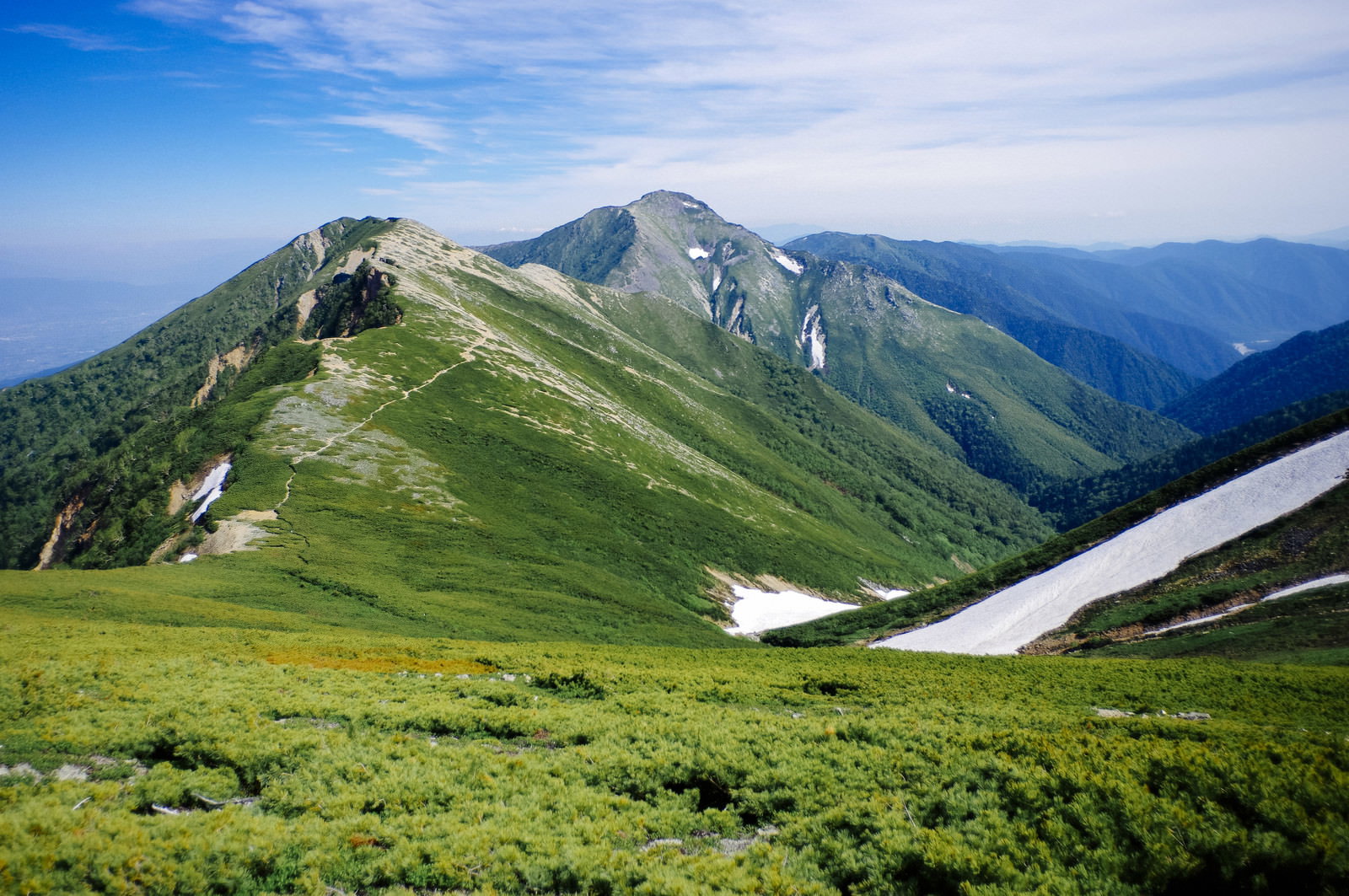 表銀座登山道から見た常念岳方面の山並み、緑の稜線と青空