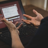 ランサムウェアの警告画面に困惑するパソコン操作の男性の写真