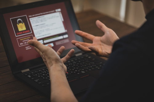 ランサムウェアの警告画面に困惑するパソコン操作の男性