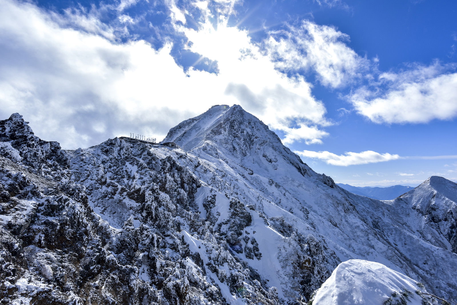 雪山の稜線と青空が広がる冬の地蔵尾根から見た赤岳の山岳風景