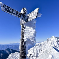 冬の北アルプス文三郎尾根稜線に立つ木製の指導標の写真