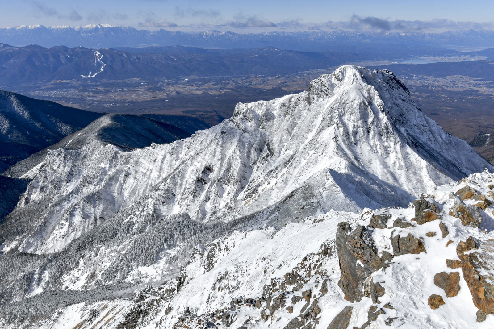雪に覆われた阿弥陀岳と南アルプスの山々を一望した冬の山岳風景